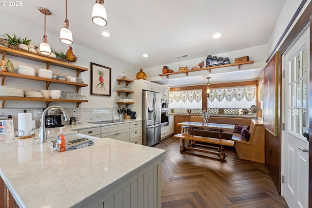 kitchen with visible vents, open shelves, decorative backsplash, stainless steel refrigerator with ice dispenser, and decorative light fixtures