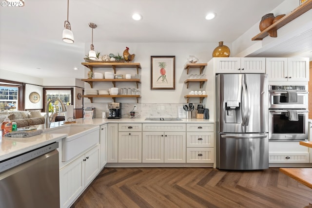 kitchen with a sink, stainless steel appliances, light countertops, and open shelves