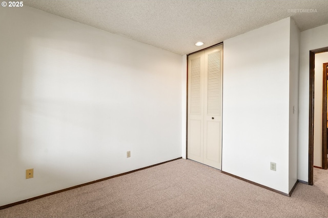 unfurnished bedroom featuring light colored carpet, a closet, baseboards, a textured ceiling, and recessed lighting