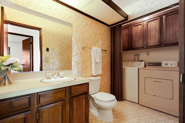 half bath featuring washing machine and clothes dryer, wallpapered walls, toilet, and vanity