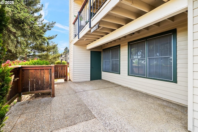 view of patio with fence and a balcony