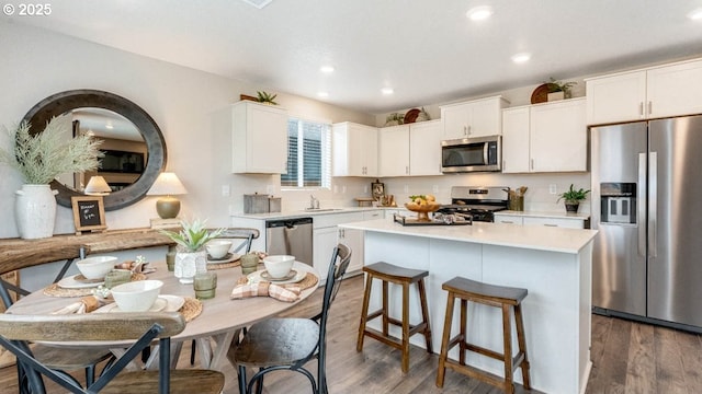 kitchen with stainless steel appliances, a sink, a center island, light countertops, and white cabinets