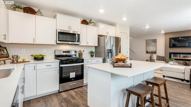 kitchen featuring stainless steel appliances, a breakfast bar, dark wood-style floors, open floor plan, and recessed lighting