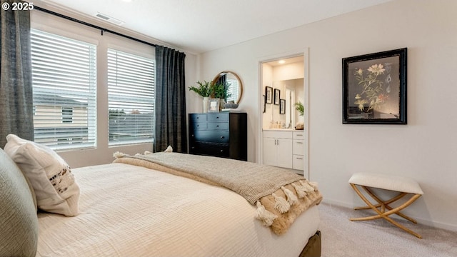 bedroom featuring multiple windows, carpet flooring, ensuite bathroom, and baseboards