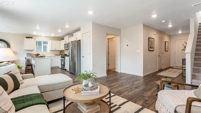 living room featuring dark wood finished floors, recessed lighting, baseboards, and stairway