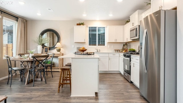kitchen featuring appliances with stainless steel finishes, a breakfast bar, white cabinets, a center island, and recessed lighting