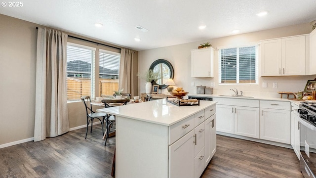 kitchen with a sink, gas range oven, light countertops, a center island, and recessed lighting