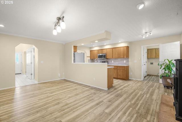 1255 NE 17th Ave, Hillsboro, OR 97124 - kitchen featuring stainless steel microwave, freestanding refrigerator, a peninsula, arched walkways, and light wood-style floors