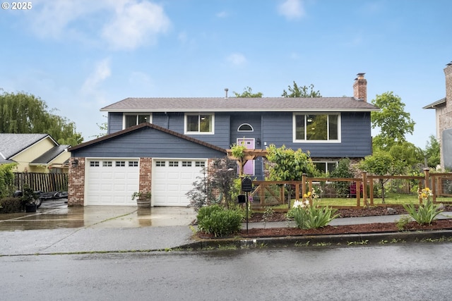 bi-level home featuring a garage, driveway, fence, a chimney, and brick siding