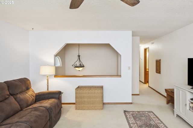 living area with a ceiling fan, light carpet, baseboards, and a textured ceiling