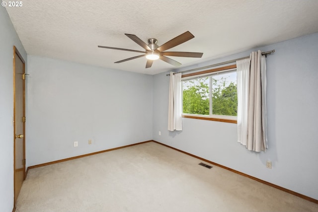 unfurnished room with ceiling fan, light colored carpet, baseboards, and a textured ceiling