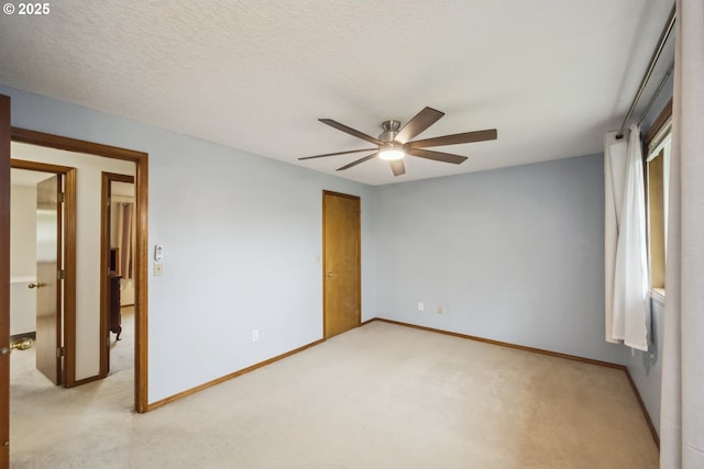 unfurnished room featuring ceiling fan, light colored carpet, and baseboards
