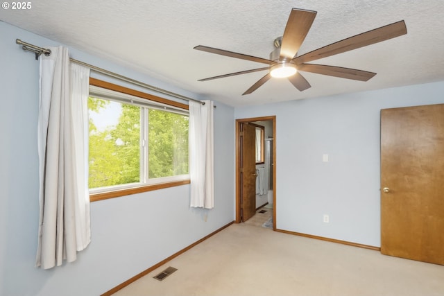unfurnished bedroom with a textured ceiling, carpet, baseboards, a ceiling fan, and ensuite bath