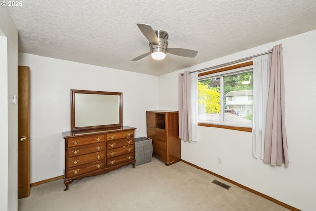 bedroom with baseboards, light colored carpet, a textured ceiling, and a ceiling fan