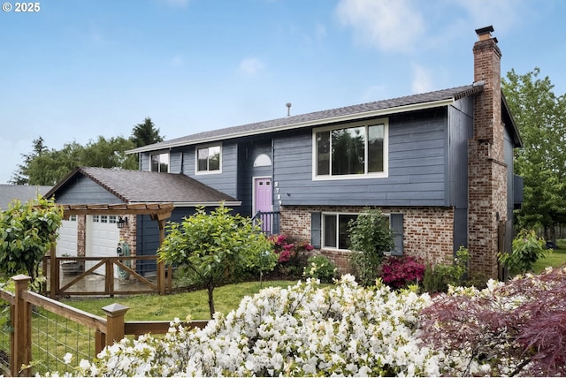 raised ranch with a chimney, brick siding, fence, and a garage