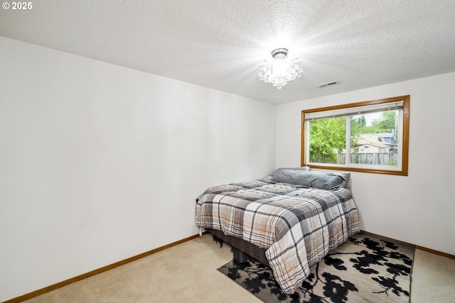 bedroom featuring baseboards, light colored carpet, a textured ceiling, and a chandelier