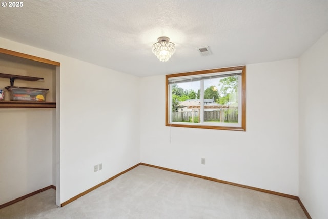 unfurnished bedroom with baseboards, a closet, light colored carpet, a chandelier, and a textured ceiling