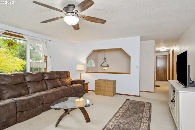 living area featuring a textured ceiling, ceiling fan, light carpet, and baseboards