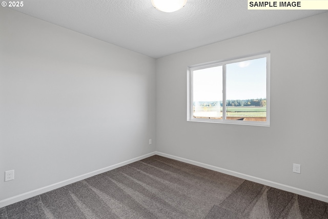 spare room with baseboards, dark carpet, and a textured ceiling