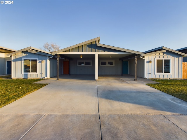 view of front of property with an attached carport, board and batten siding, driveway, and a front lawn