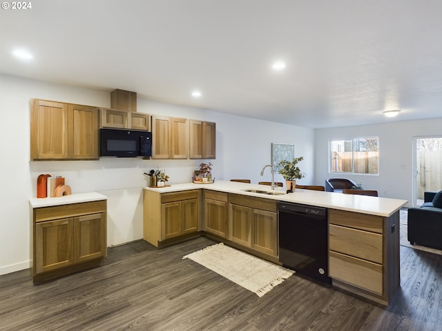 kitchen featuring black appliances, a peninsula, dark wood-style flooring, and a sink