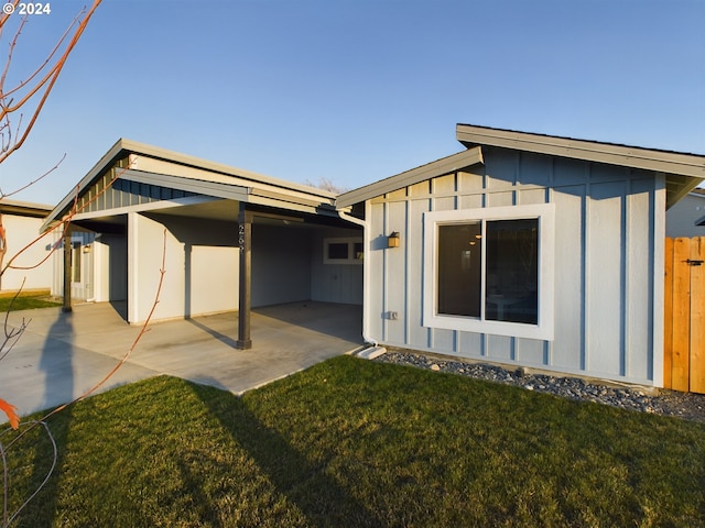 back of house featuring a patio, a yard, and board and batten siding