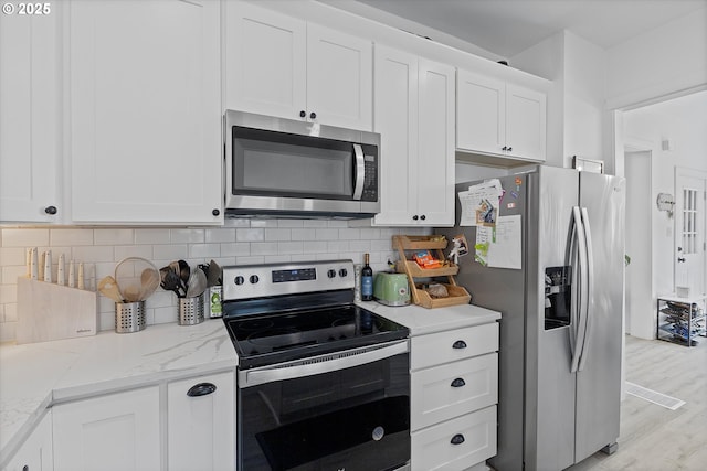 8007 N Hudson St, Portland, OR 97203 - kitchen with stainless steel appliances, white cabinets, light wood-type flooring, and backsplash