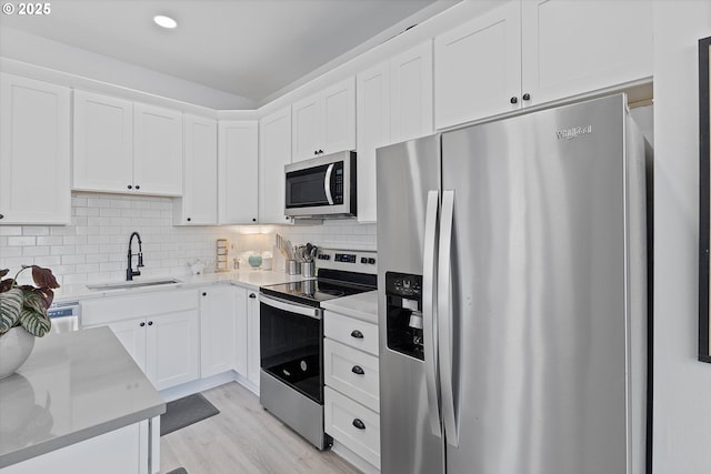 8007 N Hudson St, Portland, OR 97203 - kitchen with appliances with stainless steel finishes, white cabinetry, tasteful backsplash, light wood-type flooring, and recessed lighting
