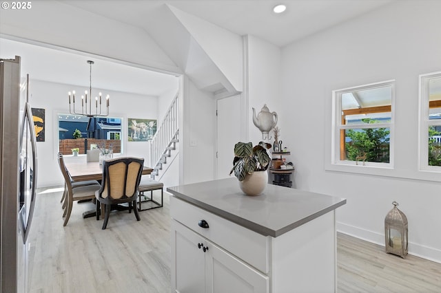 8007 N Hudson St, Portland, OR 97203 - kitchen with freestanding refrigerator, light wood-style flooring, a chandelier, white cabinets, and pendant lighting