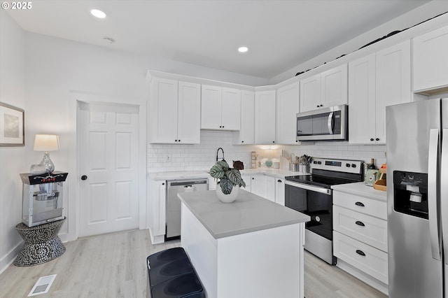 8007 N Hudson St, Portland, OR 97203 - kitchen featuring appliances with stainless steel finishes, light wood-type flooring, light countertops, white cabinets, and backsplash