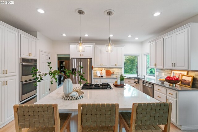 kitchen featuring appliances with stainless steel finishes, a kitchen island, backsplash, recessed lighting, and white cabinets