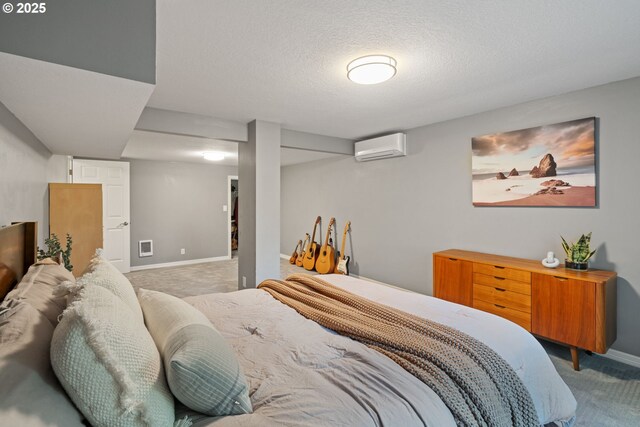 carpeted bedroom with a wall mounted air conditioner, baseboards, and a textured ceiling