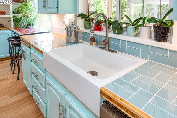 855 E 39th Ave, Eugene, OR 97405 - kitchen featuring blue cabinets, a sink, decorative backsplash, tile countertops, and plenty of natural light