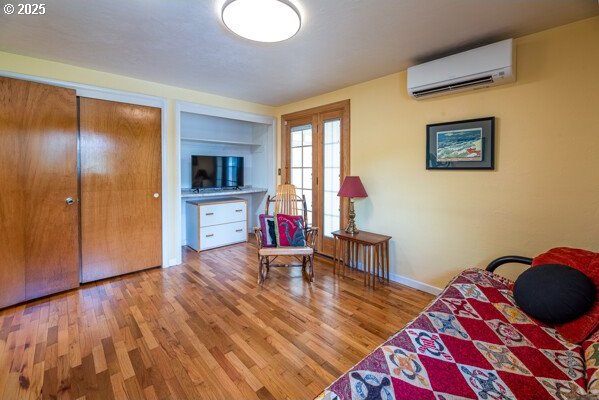 855 E 39th Ave, Eugene, OR 97405 - bedroom with a wall mounted air conditioner, wood finished floors, and baseboards