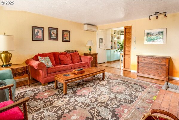 855 E 39th Ave, Eugene, OR 97405 - living area with a wall unit AC, wood finished floors, and a textured ceiling