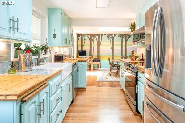 855 E 39th Ave, Eugene, OR 97405 - kitchen featuring appliances with stainless steel finishes, blue cabinetry, light wood finished floors, and a sink