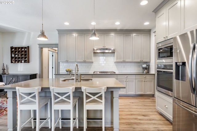 19294 Boulder Run Ct, Oregon City, OR 97045 - kitchen with appliances with stainless steel finishes, under cabinet range hood, backsplash, light wood-style flooring, and recessed lighting