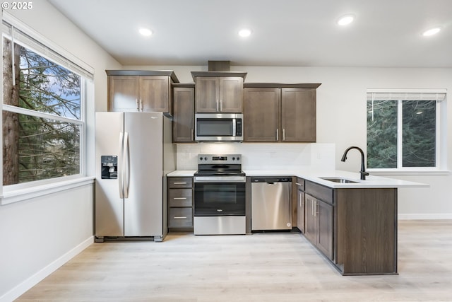 21190 SW Ortiz Ln, Beaverton, OR 97003 - kitchen featuring stainless steel appliances, a peninsula, light wood-style flooring, a sink, and baseboards