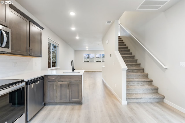 21190 SW Ortiz Ln, Beaverton, OR 97003 - kitchen featuring a sink, light wood-style floors, stainless steel appliances, light countertops, and a peninsula