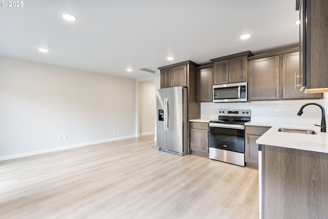 21190 SW Ortiz Ln, Beaverton, OR 97003 - kitchen featuring light wood finished floors, stainless steel appliances, a sink, dark brown cabinets, and light countertops