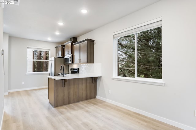 21190 SW Ortiz Ln, Beaverton, OR 97003 - kitchen with stainless steel appliances, light countertops, light wood-style floors, and a breakfast bar area