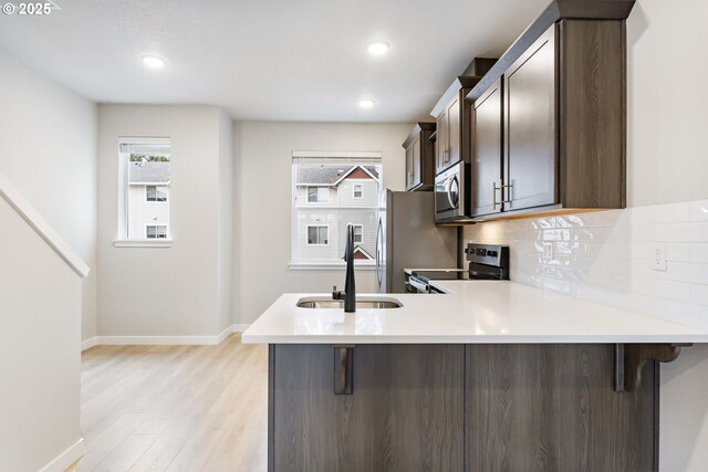 21190 SW Ortiz Ln, Beaverton, OR 97003 - kitchen with a sink, light wood-type flooring, light countertops, a peninsula, and appliances with stainless steel finishes