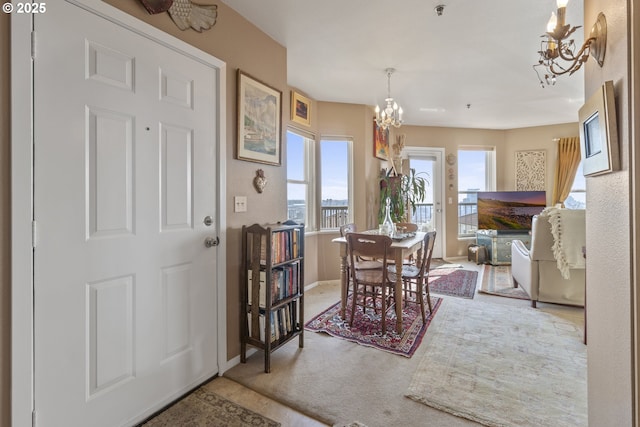 carpeted dining room with a chandelier and baseboards