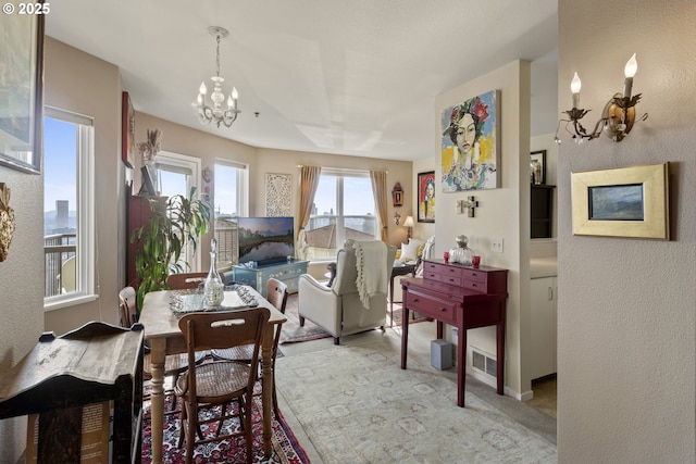 dining room featuring a chandelier, light carpet, baseboards, and a textured wall
