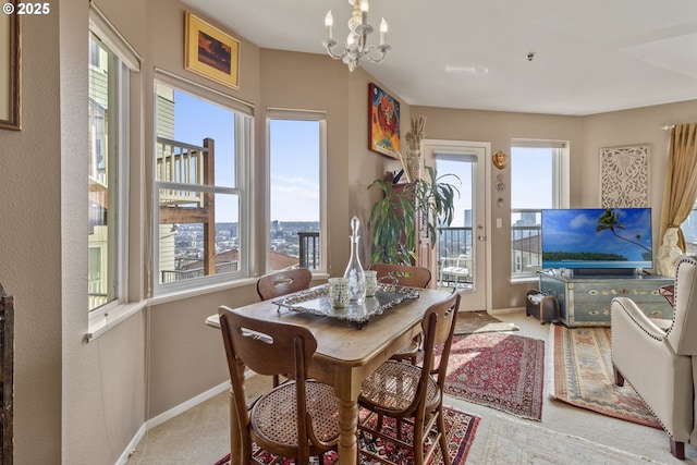 carpeted dining area featuring baseboards, a chandelier, and a textured wall
