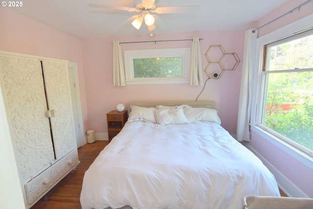 bedroom featuring a ceiling fan, baseboards, and dark wood-style floors