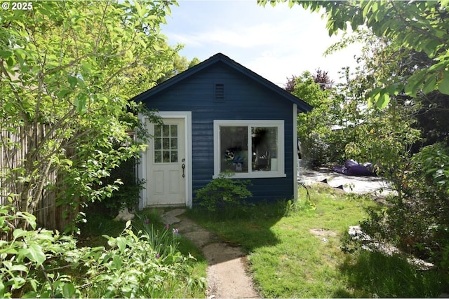 view of outbuilding featuring fence and an outbuilding