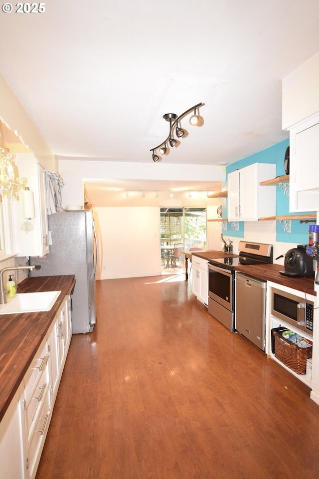kitchen with wooden counters, appliances with stainless steel finishes, open shelves, wood finished floors, and a sink