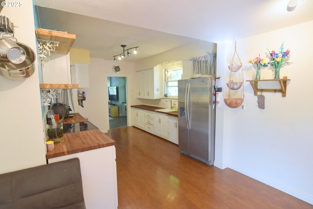 kitchen with white cabinets, dark wood-style flooring, stainless steel fridge, a sink, and butcher block counters