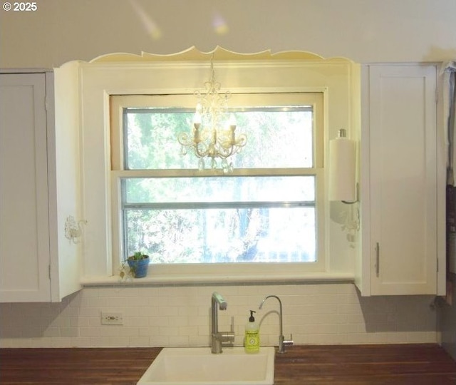 kitchen with a sink, white cabinets, and a chandelier
